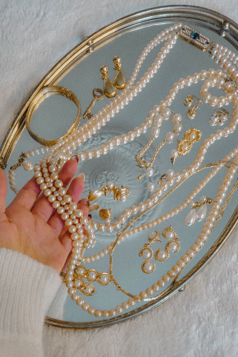 An estate buyer examining assorted jewelry pieces on a tray 